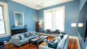 A living room with a fireplace, two sofas, a coffee table, and a ceiling fan.