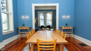 A dining room with a wooden table and chairs, blue walls, and a window with a view.