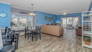 A living room with a sofa, dining table, chairs, and a TV. - Magnolia N 201 (Myrtle Beach)