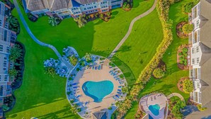 An aerial view of a resort with a central swimming area, multiple pools, and surrounding greenery. - Magnolia N 201 (Myrtle Beach)