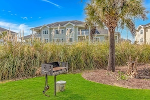 A residential area with houses, a barbecue grill, and a palm tree. - Magnolia N 201 (Myrtle Beach)