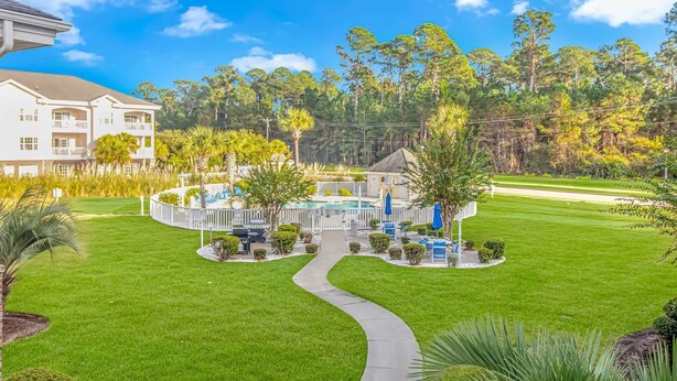A resort with a swimming pool, a walking path, and a building with balconies. - Magnolia N 201 (Myrtle Beach)
