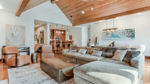 A spacious living room with a large sectional sofa, a wooden coffee table, and a dining area with wooden chairs. - 2 Minute Walk to Cascade Lift + Luxury Penthouse Condo with Covered Parking (Vail)