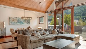 A spacious living room with a large sectional sofa, a coffee table, and a dining area with a table and chairs. - 2 Minute Walk to Cascade Lift + Luxury Penthouse Condo with Covered Parking (Vail)