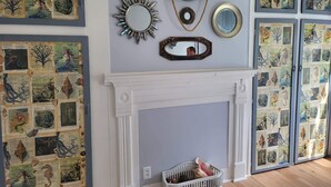 A room with a fireplace, multiple mirrors, and a wall decorated with nautical-themed artwork. - Mermaid Tale-Bohemian Bungalow (Dayton)