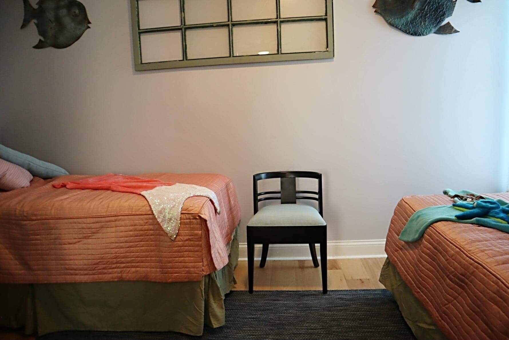 A bedroom with two beds, a chair, and a window with a grid pattern.