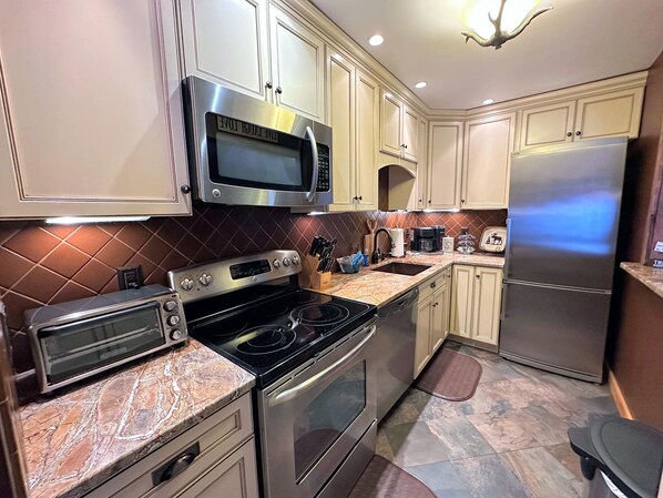 Una cocina equipada con microondas, estufa, horno y refrigerador.