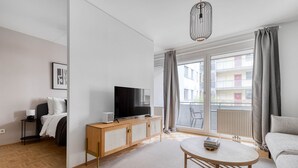 A modern living room with a flat-screen TV on a wooden cabinet, a round coffee table, and a sofa. - Modern Leopoldstadt 1BR w/ Balcony & Elevator, nr metro U2, by Blueground (Vienna)