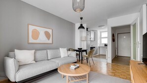 A modern living room with a grey sofa, a round wooden coffee table, and a dining area with a table and chairs. - Modern Leopoldstadt 1BR w/ Balcony & Elevator, nr metro U2, by Blueground (Vienna)