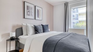 A bedroom with a bed, bedside table, lamp, and artwork on the wall. - Modern Leopoldstadt 1BR w/ Balcony & Elevator, nr metro U2, by Blueground (Vienna)