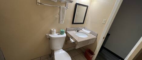 A bathroom with a toilet, sink, towel rack, and a mirror.