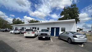 A parking lot with several cars parked in front of a building with a blue door and windows. - Country Inn-Giddings (Giddings)