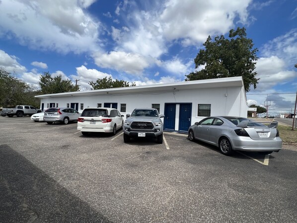 A parking lot with several cars parked in front of a building with a blue door and windows. - Country Inn-Giddings (Giddings)