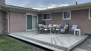 A patio with a table and chairs, a grill, and a deck. - private 6 Bedroom charming  2000 sq ft ranch 10-14 people (Sterling Heights)