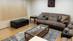A living room with a sofa, ottoman, coffee table, and a small side table. - private 6 Bedroom charming  2000 sq ft ranch 10-14 people (Sterling Heights)