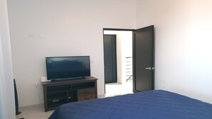 A bedroom with a bed, a TV on a stand, and a door leading to a balcony. - New Town Condo Casamar 2 near the beach (Puerto Peñasco)