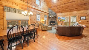 A wooden cabin interior with a dining table, chairs, a fireplace, and a sofa. - Cabin with Appalachian Mountain Views (Boone)