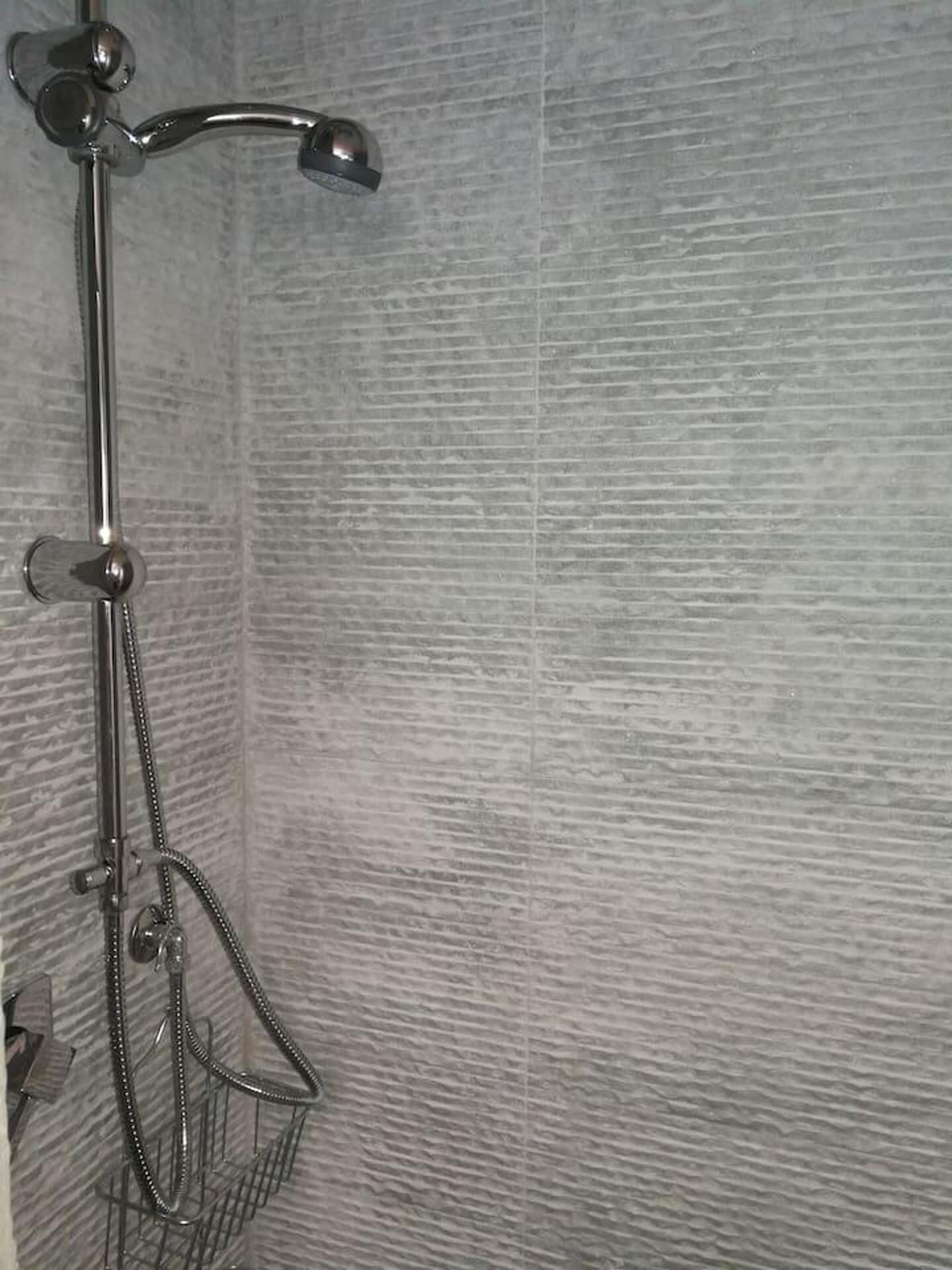 A shower with a handheld showerhead and a handheld shower attachment.