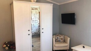 A room with a white wardrobe, a beige armchair, a small white table, and a flat-screen TV mounted on the wall. - Beautiful Lux Apartment Chianti Firenze Area Italy (Barberino Tavarnelle)