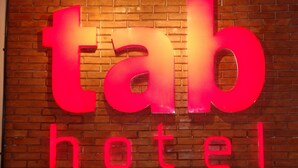 Une enseigne d’hôtel avec le nom « tab hotel » écrit en gros caractères et en gras, sur un mur de briques.