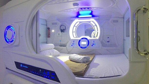Une salle d’imagerie médicale équipée d’un lit, de panneaux de commande et d’un luminaire circulaire.