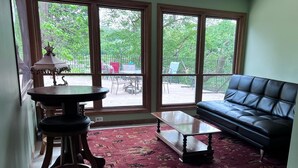 A living room with a black leather sofa, a round table with a lamp, and a patterned carpet. - Enjoy Florida in Illinois; House on Island with Pool (East Moline)