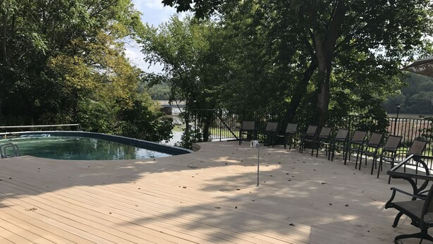 A wooden deck with a pool, surrounded by trees and outdoor seating. - Enjoy Florida in Illinois; House on Island with Pool (East Moline)