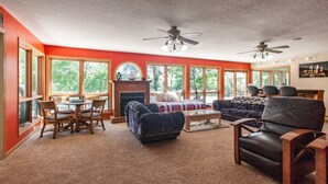 A living room with a fireplace, a sofa, a coffee table, and a dining area with chairs. - Enjoy Florida in Illinois; House on Island with Pool (East Moline)