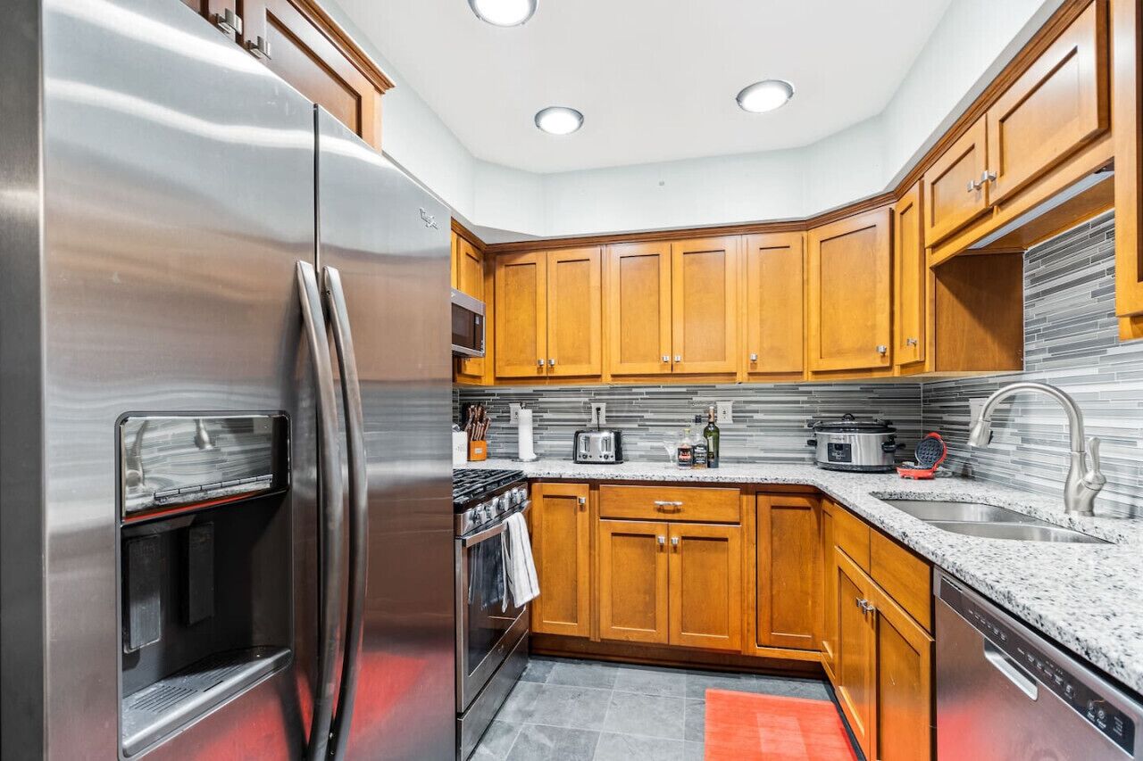 A compact kitchen with wooden cabinets, stainless steel appliances, and a granite countertop.