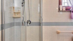A shower with a glass door, a wooden shelf, and a towel rack.