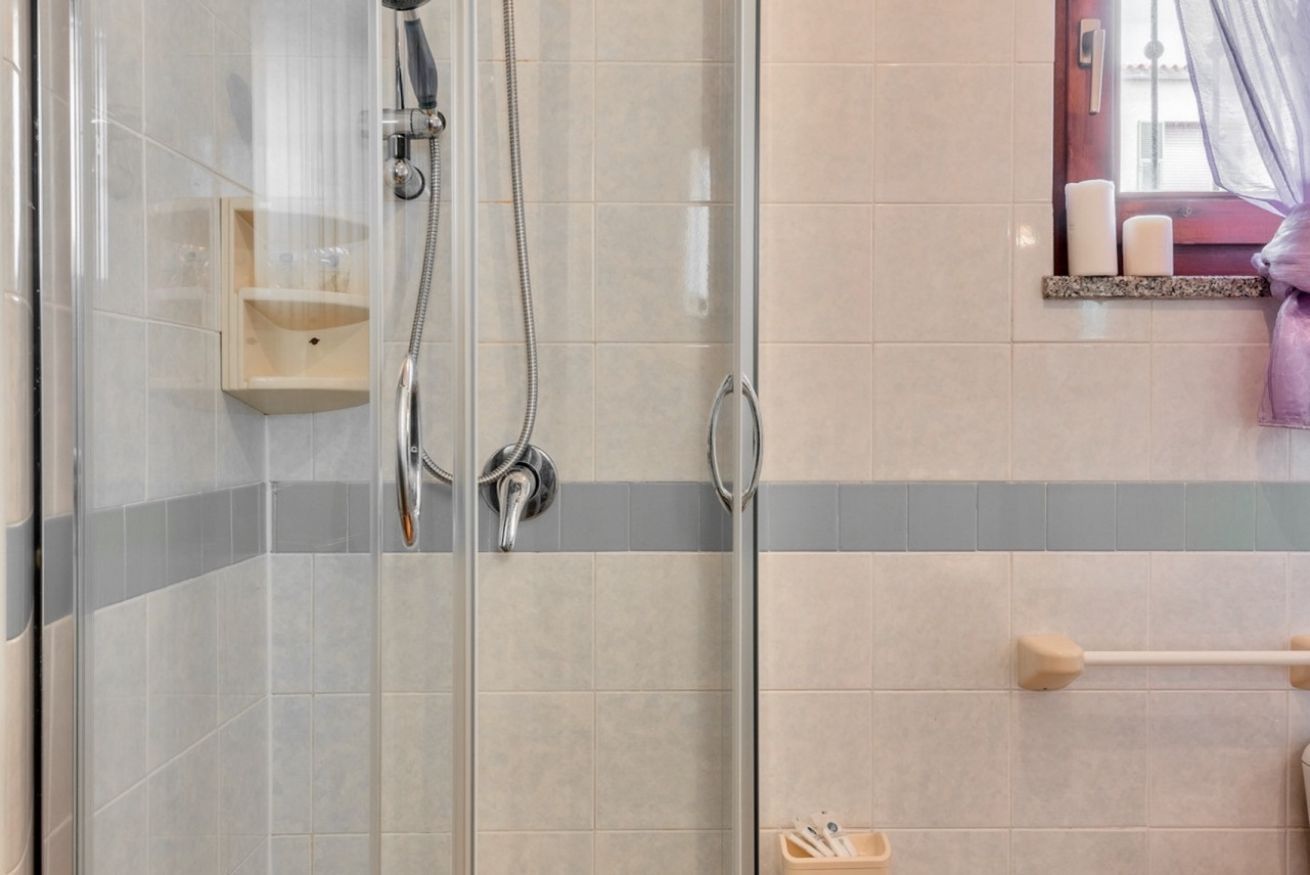 Eine Dusche mit Glastür, einem Holzregal und einem Handtuchhalter.