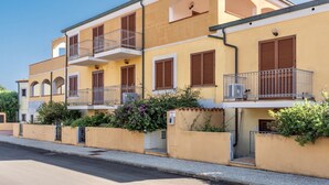 A multi-story residential building with balconies, a central courtyard, and a street view.