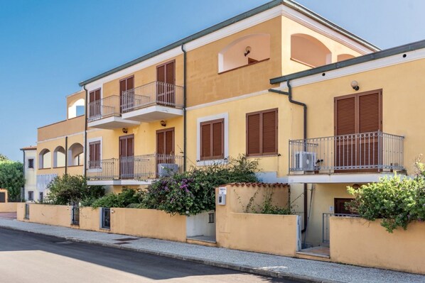 Un immeuble résidentiel à plusieurs étages, doté de balcons, d’une cour intérieure et donnant sur la rue.