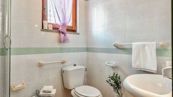 Une salle de bain équipée de toilettes, d’un lavabo et d’une fenêtre avec un rideau.