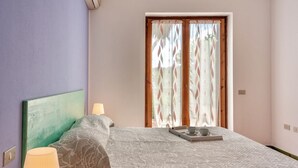 A bedroom with a bed, a bedside lamp, a tray with a cup and saucer, and a window with curtains. - (45 sq m): living room with induction cooker, double sofa bed, double bedroom, bathroom. <br>The apartments are equipped with: <br>iron and ironing board (on request), <br><b>air conditioning</b>, <br>kitchenette with induction hob <br>tv <br>microwave,  (Santa Teresa di Gallura)