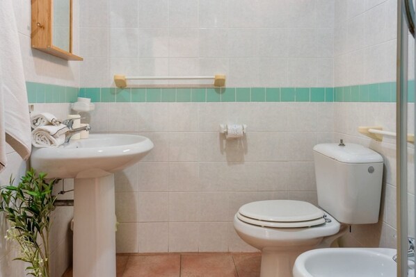 A bathroom with a sink, toilet, bidet, and a mirror.