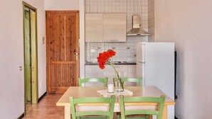A kitchen with a wooden door, white tiled backsplash, and a dining area with a table and chairs. - (45 sq m): living room with induction cooker, double sofa bed, double bedroom, bathroom. <br>The apartments are equipped with: <br>iron and ironing board (on request), <br><b>air conditioning</b>, <br>kitchenette with induction hob <br>tv <br>microwave,  (Santa Teresa di Gallura)