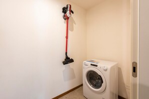 A laundry area with a washing machine and a wall-mounted vacuum cleaner.
