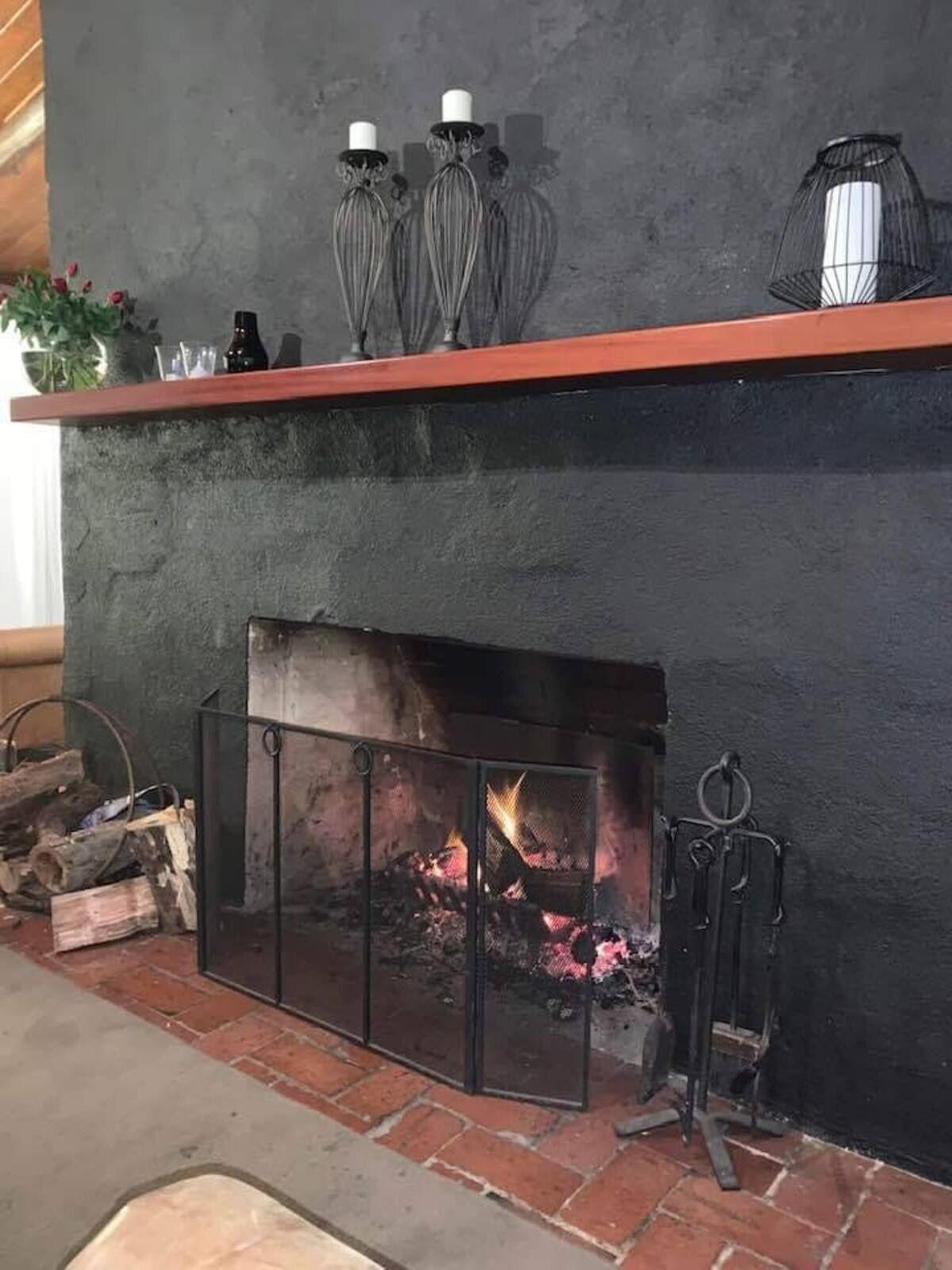 A fireplace with a fire, a mantel with decorative items, and a brick floor.