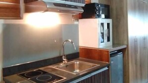 A modern kitchen with dark wood cabinets, stainless steel appliances, and a built-in dishwasher. - Stunning Studio Type - 1641 - 16th Flr Persimmon (Cebu)