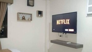 A hotel room with a bed, a TV mounted on the wall, and a small shelf below the TV. - Stunning Studio Type - 1641 - 16th Flr Persimmon (Cebu)
