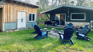 Une cabane en bois dotée d’un porche couvert, de meubles d’extérieur et d’un barbecue.