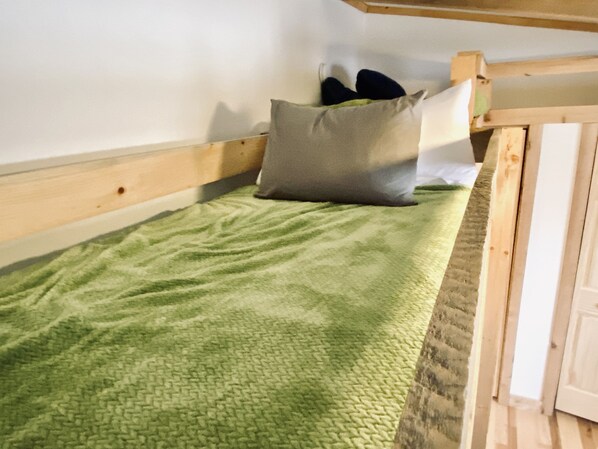 A single bed with a green blanket, a grey pillow, and a wooden headboard. - Cozy Lakefront Cabin with Private Dock, Firepit, Grill, Kayaks and More! (Hayward)
