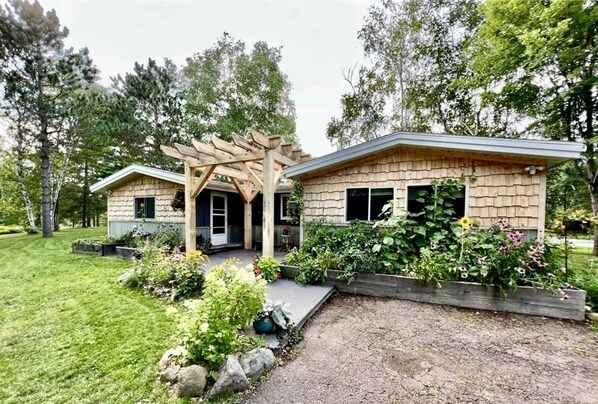 Une maison à deux étages avec un patio couvert et un jardin.