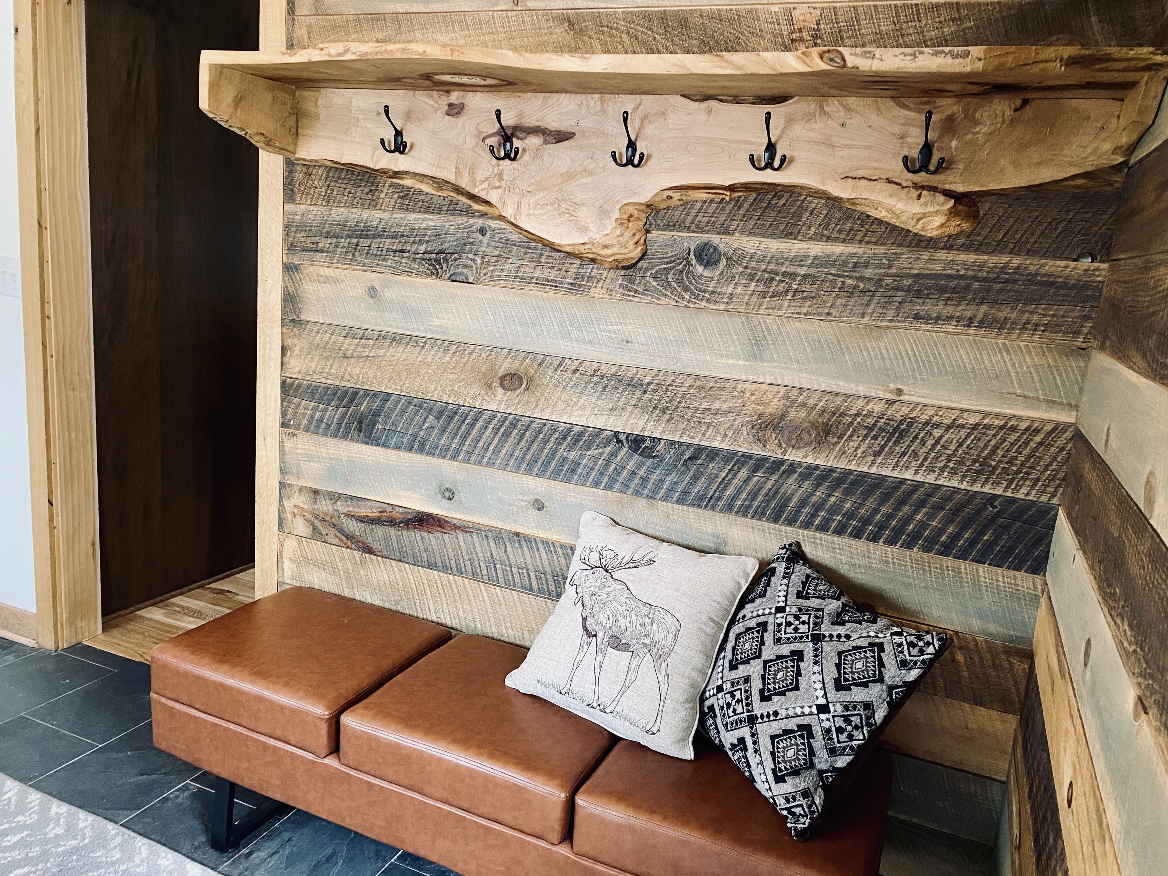 Een houten wand met een rustieke inrichting, een bankje en een decoratief kussen.