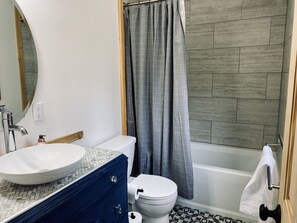Une salle de bain avec un lavabo blanc, des toilettes et une baignoire.