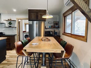 Une cuisine moderne avec une table à manger en bois, des chaises et un four encastré.
