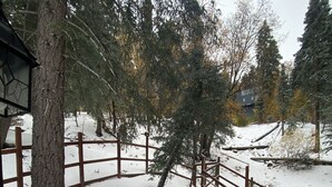 A snow-covered outdoor area with a wooden deck, a chair, and a table.