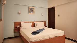 Habitación de hotel ordenada con cama, mesitas de noche, un cuadro en la pared y un equipo de aire acondicionado.