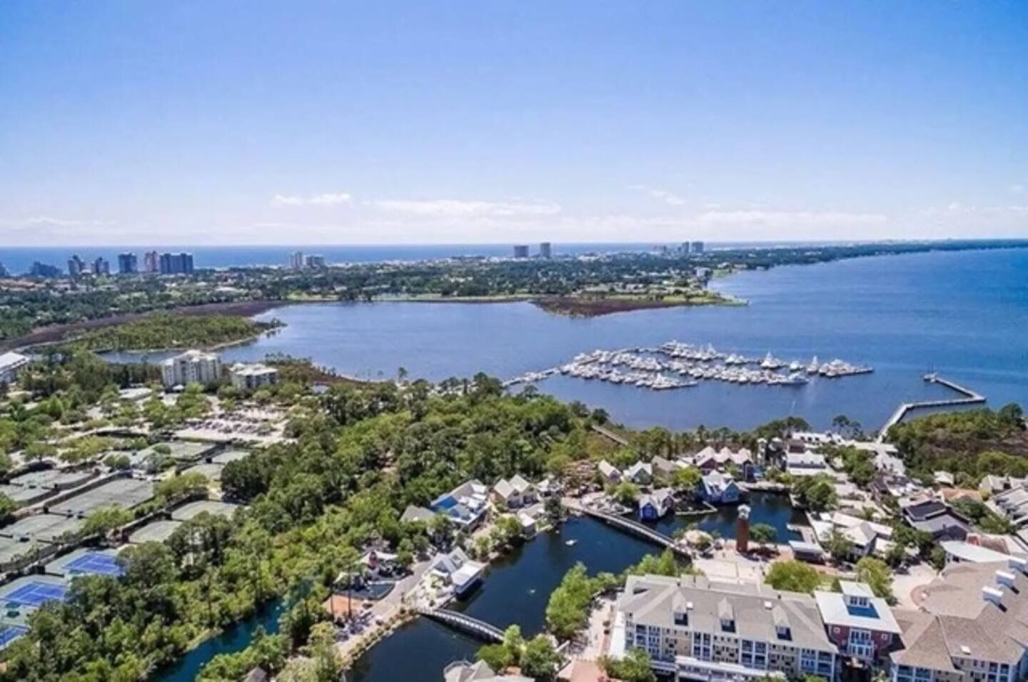 Vista aérea de una zona costera con edificios residenciales, un puerto deportivo y una extensa masa de agua.